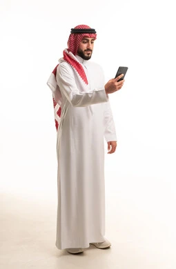 رجل سعودي بالثوب التقليدي يستخدم الهاتف الذكي