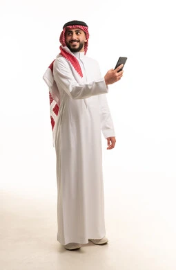 رجل سعودي بالزي التقليدي يحمل هاتفاً ذكياً