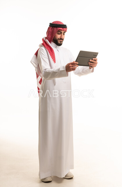 رجل سعودي يحمل جهاز لوحي بخلفية بيضاء