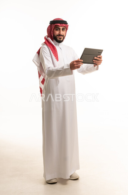 رجل سعودي بالزي التقليدي يحمل جهاز لوحي رقمي