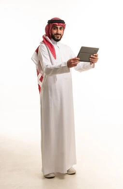 رجل سعودي بالزي التقليدي يحمل جهاز لوحي رقمي
