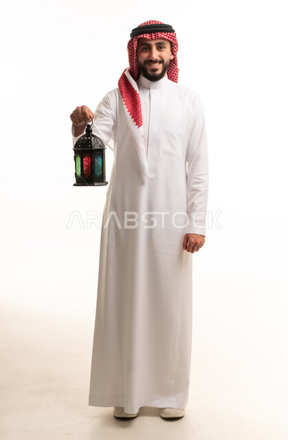 رجل سعودي يحمل فانوس رمضان التقليدي بخلفية بيضاء