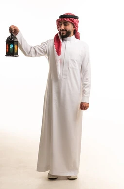 رجل سعودي يمسك فانوس رمضان التقليدي بخلفية بيضاء