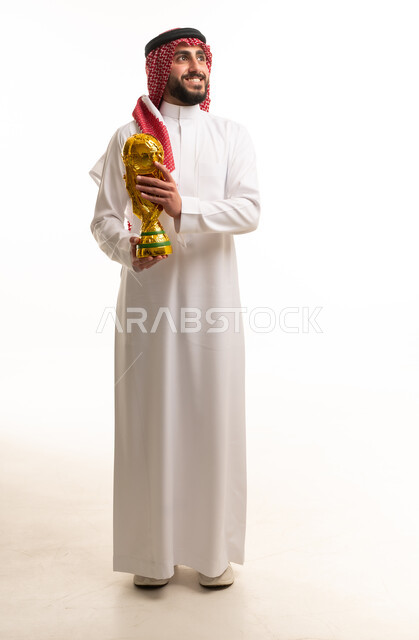 رجل سعودي بالزي التقليدي يحمل كأس العالم