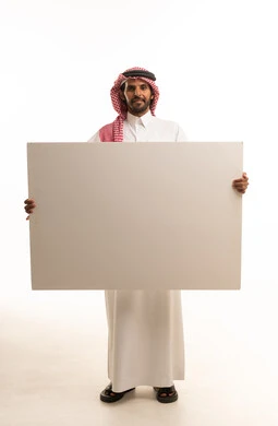 رجل سعودي يحمل لوحة بيضاء فارغة أمام خلفية بيضاء