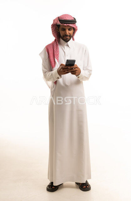 رجل سعودي بالزي التقليدي يستخدم الهاتف الذكي