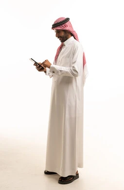 رجل سعودي بالثوب التقليدي يستخدم جهاز لوحي