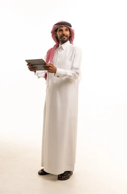 رجل سعودي يحمل جهازاً لوحياً بخلفية بيضاء