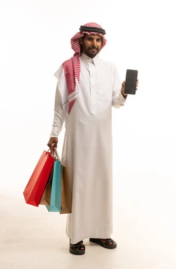 رجل سعودي مع حقائب تسوق وهاتف ذكي خلفية بيضاء