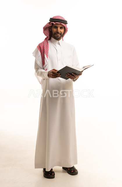 رجل سعودي بالثوب يحمل كتاباً على خلفية بيضاء