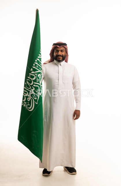 رجل سعودي يحمل العلم الوطني بالزي التقليدي