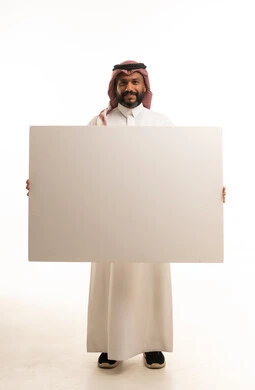 رجل سعودي يحمل لوحة بيضاء فارغة معزولة