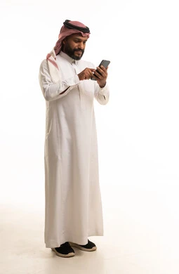 Saudi Man in Traditional Thobe Using Smartphone