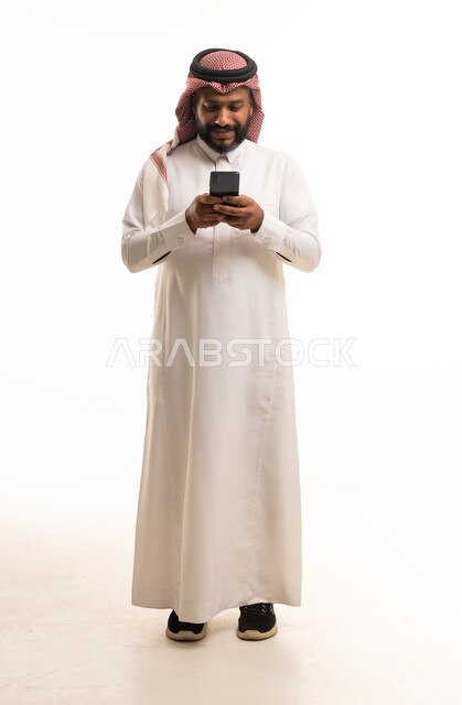 رجل سعودي يرتدي الثوب التقليدي يستخدم الهاتف الذكي