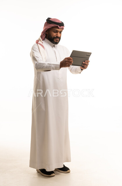رجل سعودي يستخدم جهاز لوحي على خلفية بيضاء