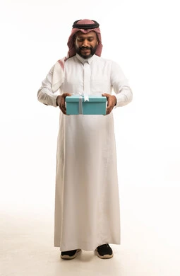 رجل سعودي يحمل صندوق هدايا أزرق بخلفية بيضاء