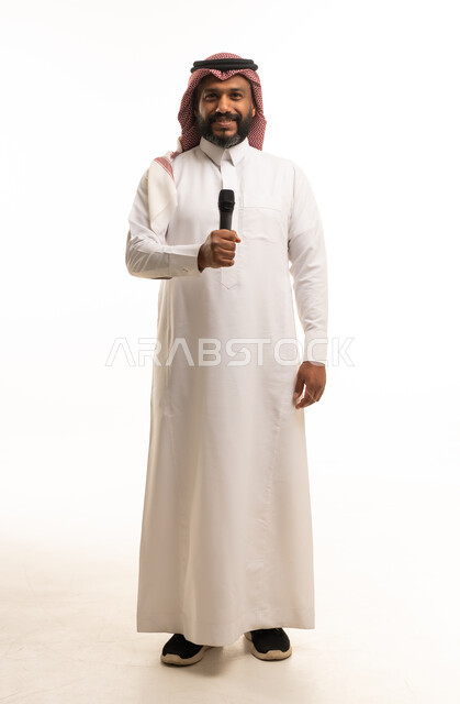 رجل سعودي يحمل ميكروفوناً بالثوب الأبيض بخلفية بيضاء