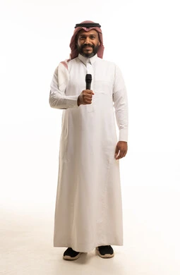 رجل سعودي يحمل ميكروفوناً بالثوب الأبيض بخلفية بيضاء