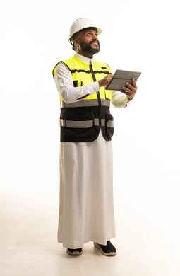مهندس سعودي يرتدي سترة السلامة ويحمل جهاز لوحي