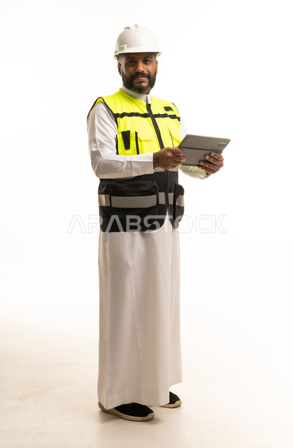 مهندس سعودي بمعدات السلامة يحمل جهاز لوحي رقمي