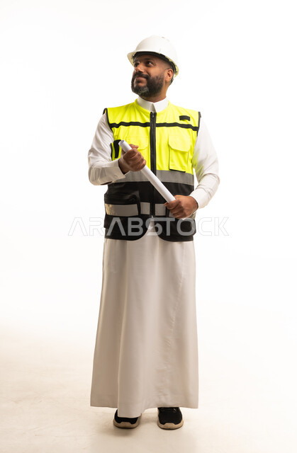 مهندس سعودي يرتدي سترة السلامة ويحمل مخططات هندسية