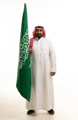رجل سعودي يحمل علم المملكة العربية السعودية