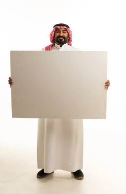 رجل سعودي يحمل لوحة إعلانية بيضاء فارغة في الاستوديو