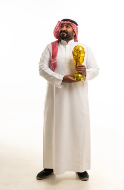 رجل سعودي يحمل كأساً ذهبياً على خلفية بيضاء