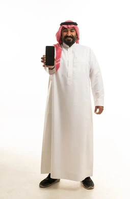 رجل سعودي يحمل هاتفاً ذكياً على خلفية بيضاء