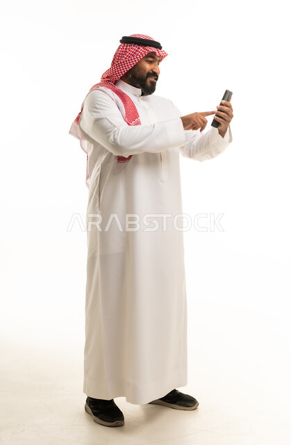 Saudi Man in Traditional Thobe Using Smartphone Studio