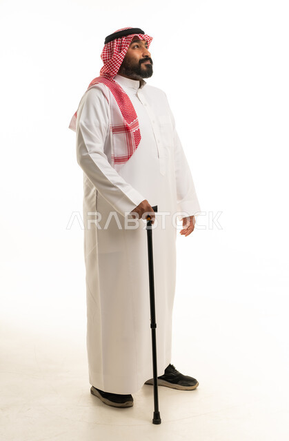 رجل سعودي بالزي التقليدي يمسك عصا مشي