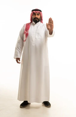 رجل سعودي بالثوب التقليدي يشير بعلامة التوقف بيده