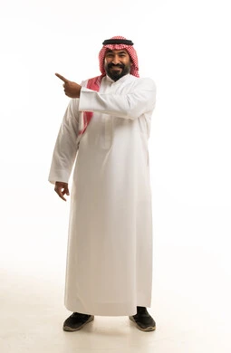 رجل سعودي يرتدي الثوب التقليدي يشير لجانب بخلفية بيضاء