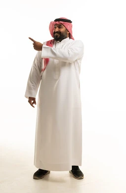 رجل سعودي بالثوب التقليدي يشير إلى الجانب