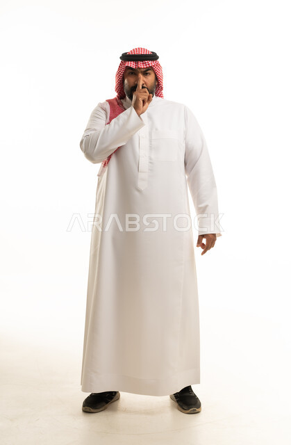 رجل سعودي بالزي التقليدي يشير بالصمت خلفية بيضاء