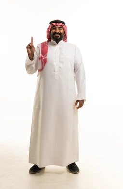رجل سعودي مبتسم يشير للأعلى على خلفية بيضاء ساطعة