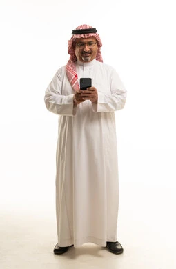 رجل سعودي بالثوب الأبيض يستخدم الجوال بخلفية بيضاء
