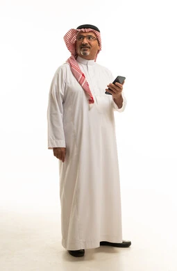 رجل سعودي بزي تقليدي مع هاتف ذكي خلفية بيضاء