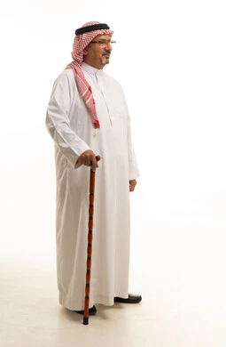 رجل سعودي بالزي التقليدي يمسك عصا المشي