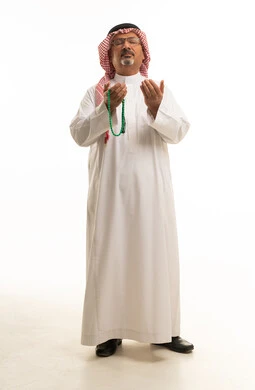 Saudi Man in Traditional Thobe Praying with Prayer Beads