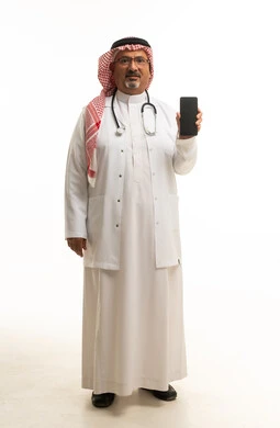 طبيب سعودي يحمل هاتفاً ذكياً على خلفية بيضاء