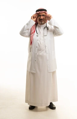 طبيب سعودي يرتدي معطفاً طبياً ويضبط نظارته