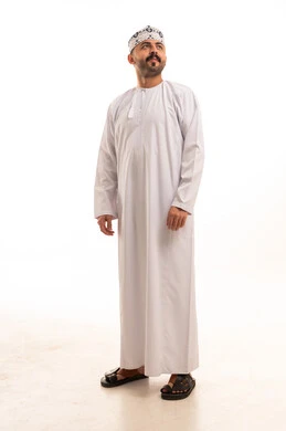 رجل عماني بالدشداشة والكمة التقليدية على خلفية بيضاء