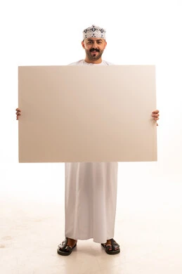 رجل عماني يحمل لوحة إعلانية بيضاء فارغة في استوديو