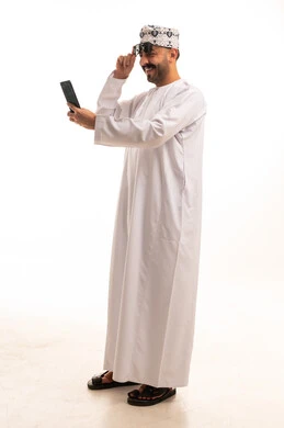 رجل عماني بالزي التقليدي يستخدم الهاتف الذكي