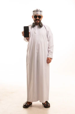 رجل عُماني بالزي التقليدي والكمة يحمل هاتفاً ذكياً