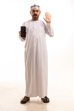 رجل عماني يحمل هاتف ذكي بتعبير مندهش