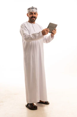 رجل عماني بالزي التقليدي يمسك جهاز لوحي