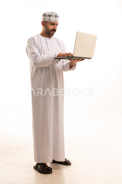 Omani Man Using Laptop in Traditional White Dishdasha