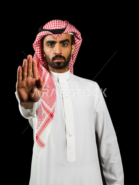 رجل عربي سعودي خليجي يرتدي الزي السعودي, إيماءات يدين تدل على الأمر بالتوقف عن فعل شيء ما, النهي عنه, الشعور بالإنزعاج, الرفض والإمتناع, خلفيه سوداء